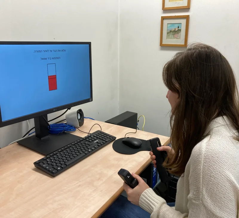 A participant squeezing a handgrip while watching the target on a computer screen